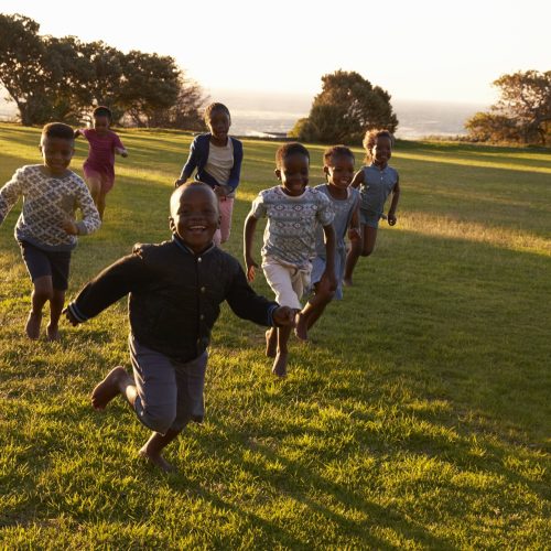 African elementary school kids running to camera in a field